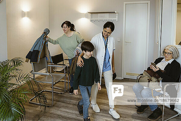 Eine Ärztin bringt einen Jungen in den Untersuchungsraum eines Krankenhauses
