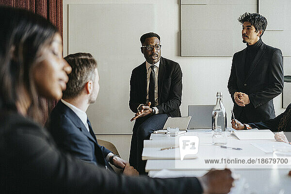 Männlicher Unternehmer plant Geschäftsstrategie mit Kollegen während einer Besprechung im Büro