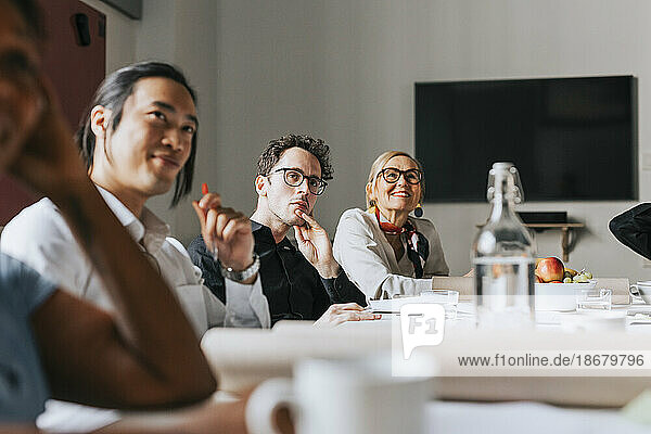 Männliche und weibliche Geschäftsleute  die an einer Sitzung im Sitzungssaal eines Büros teilnehmen
