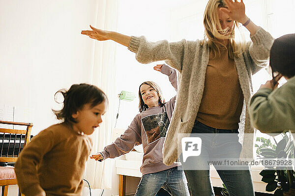 Glückliche Frau tanzt und vergnügt sich mit Kindern zu Hause