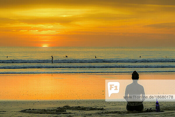 Girl and surfers silhouetted by sunset at this hip surf beach and yoga destination  Playa Guiones  Nosara  Guanacaste  Costa Rica  Central America
