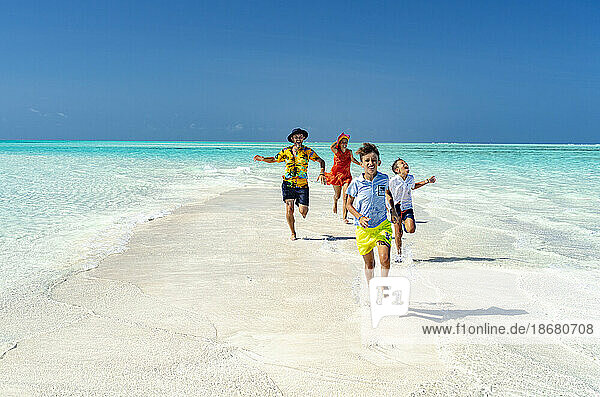 Cheerful parents with sons having fun running on an idyllic empty beach  Zanzibar  Tanzania  East Africa  Africa