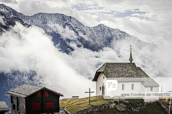 Foggy sky over the small church in the alpine village of Bettmeralp  canton of Valais  Switzerland  Europe