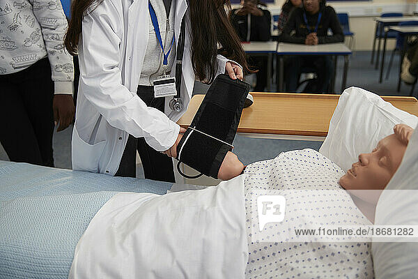 Medical students practicing measuring blood pressure on dummy