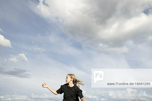 Blond girl (10-11) in black blouse against sky