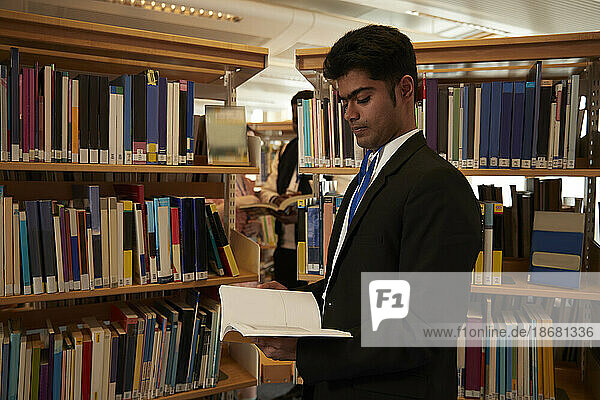 University student reading books in library