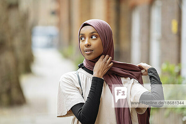 Young woman adjusting hijab outdoors