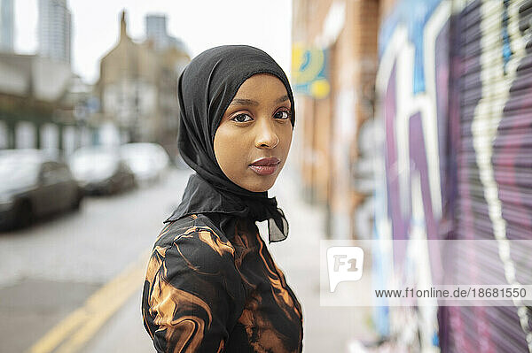 Portrait of young woman in hijab walking in street