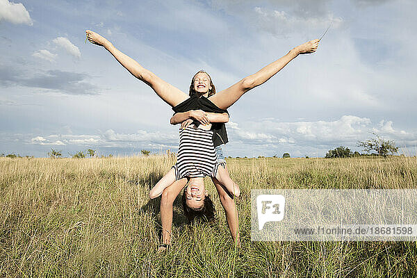 Smiling girl (10-11) holding friend upside down