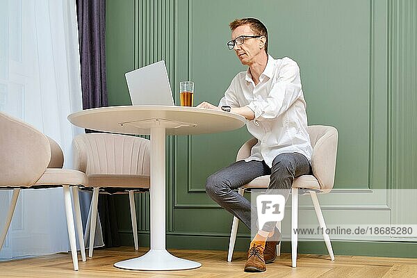Mann mittleren Alters benutzt einen Laptop zu Hause im Wohnzimmer