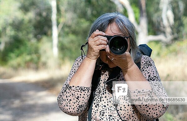 White-haired female photographer seen from the front taking pictures with her camera