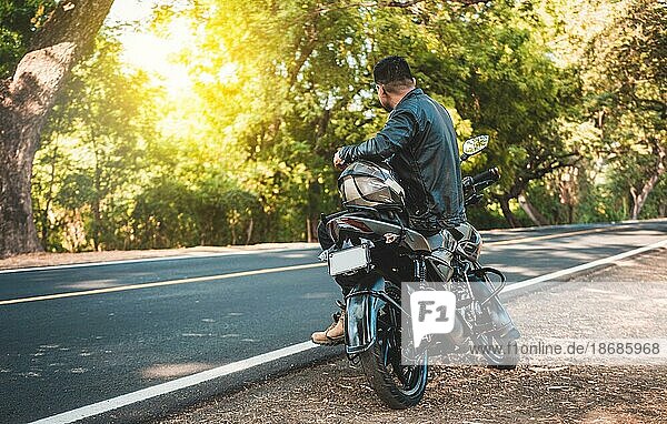 Motorradfahrer sitzt auf seinem Motorrad am Straßenrand. Mann auf seinem Motorrad sitzend am Straßenrand