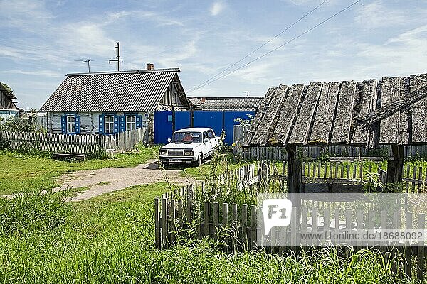 Traditionelles Holzhaus mit weißem Auto  Lada Riva  Lada Nova in einem ländlichen Dorf in Südsibirien  Russland  Europa