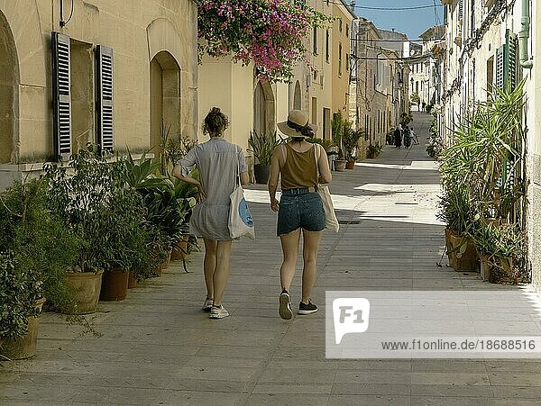 Zwei spazierende Mädchen auf der Straße in der Altstadt von Alcudia  Mallorca