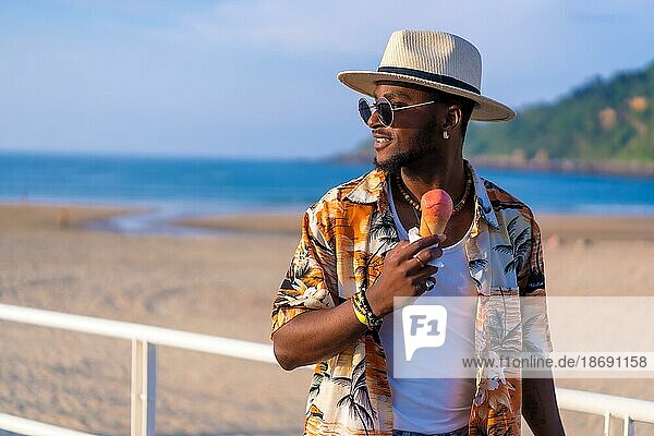Schwarze ethnische Mann genießen Sommerurlaub am Strand essen ein Eis genießen schlendern