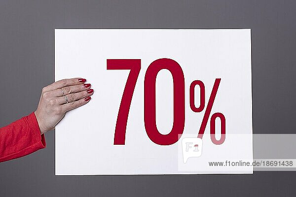 Weibliche Hand hält ein 70% Plakat. Studioaufnahme. Werbekonzept