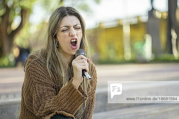 Young blonde woman singing in the street. Singer performing in the street