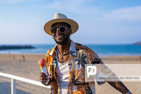 Black ethnic man enjoy summer vacation on the beach eating ice cream