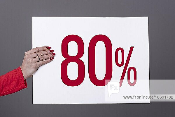 Weibliche Hand hält ein 80% Plakat. Studioaufnahme. Werbekonzept