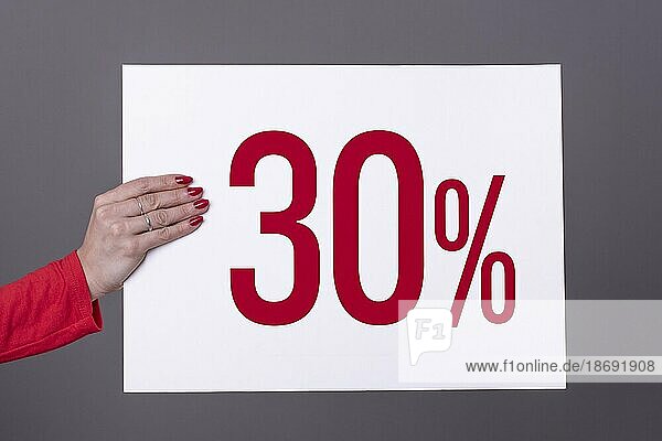 Weibliche Hand hält ein 30% Plakat. Studioaufnahme. Werbekonzept