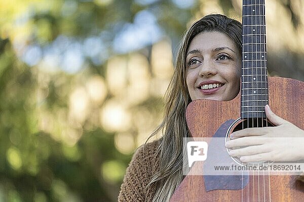 Junge blonde Frau mit ihrer Gitarre im Park. Konzept der kreativen Hobbys und Profis. Positive Einstellung. Ermächtigung