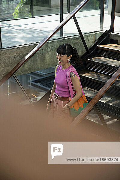 Happy woman with bag standing on staircase