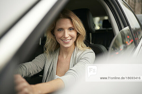 Smiling blond woman driving car