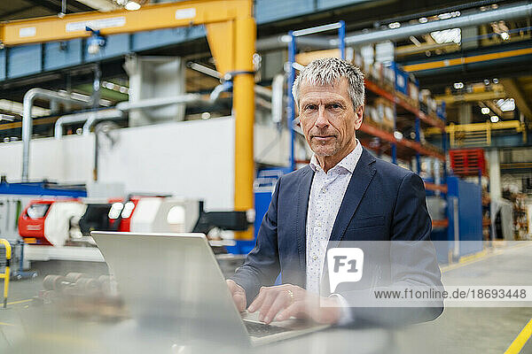 Businessman wearing suit by laptop at factory