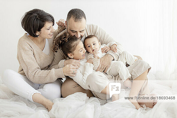 Happy family enjoying together sitting in front of white wall