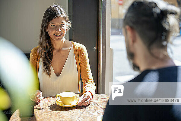 Smiling woman having coffee with man at cafe