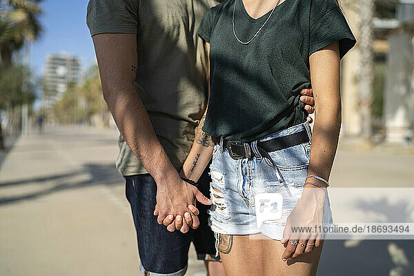 Junges Paar hält Händchen am Strand an einem sonnigen Tag