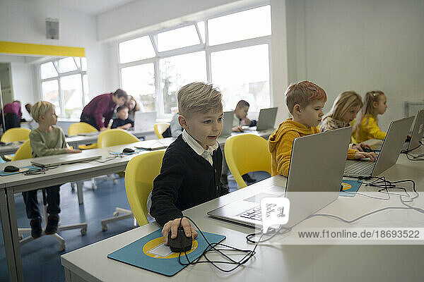 Schoolchildren studying through laptops in computer class