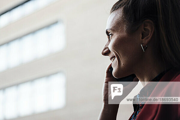Lächelnde Geschäftsfrau  die über Mobiltelefon kommuniziert