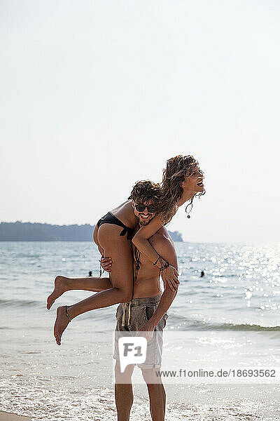 Man carrying girlfriend on shoulder at beach