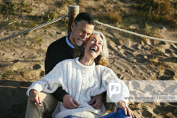 Glückliche Frau genießt es mit einem Mann  der am Strand sitzt