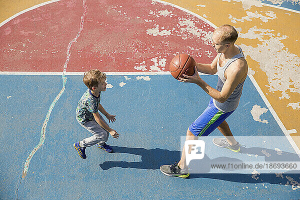 Vater und Sohn spielen Basketball auf dem Platz