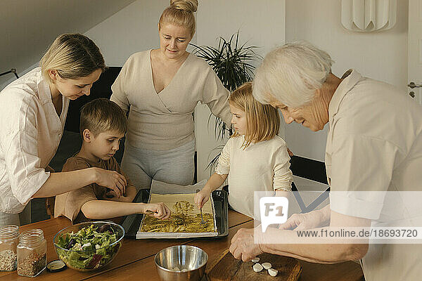 Multi-generation family assisting each other preparing food at home