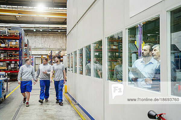 Employees walking together in production hall at factory