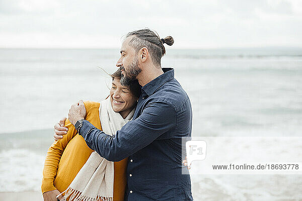 Reifer Mann umarmt Frau am Strand