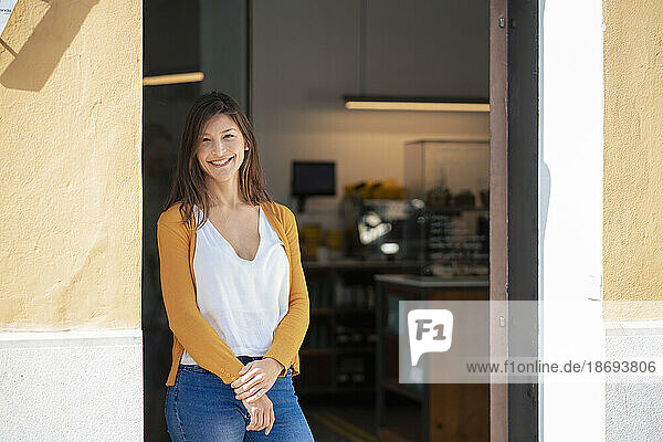 Smiling owner standing at coffee shop doorway