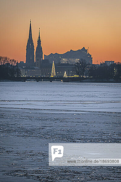 Germany  Hamburg  Ice floating in Alster Lake at dusk with city skyline in background