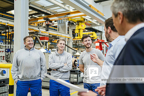 Manager explaining to employees in meeting at factory
