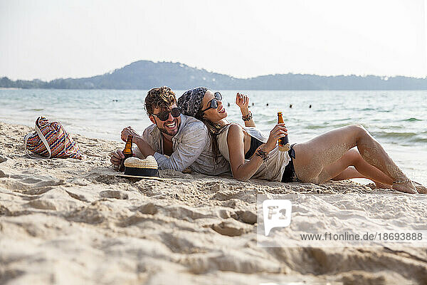 Happy couple spending leisure time lying on sand at beach