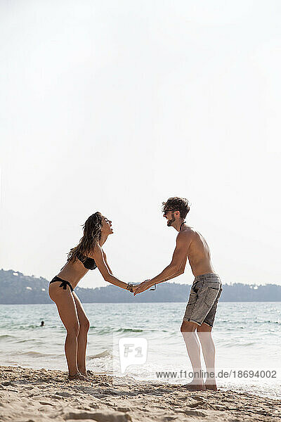 Paar hält Händchen und steht am Strand