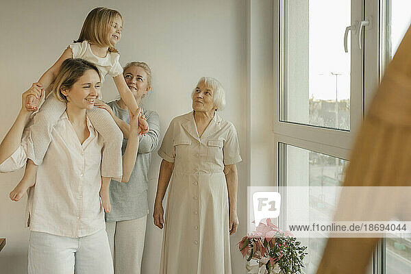 Familie genießt mit Enkelin am Fenster zu Hause