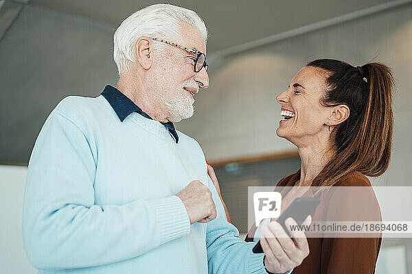 Laughing young woman and senior man with smart phone