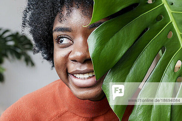 Smiling young woman with monstera leaf