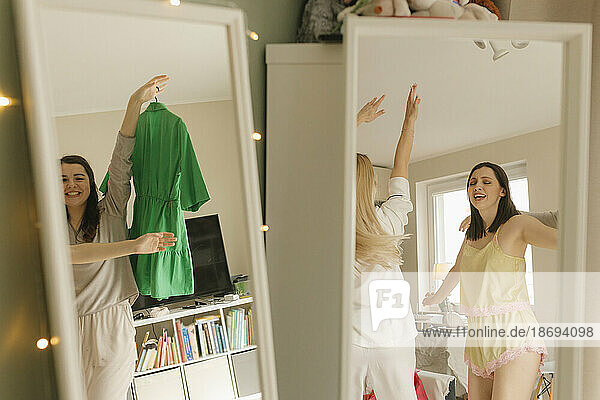 Carefree friends dancing at home seen in mirror