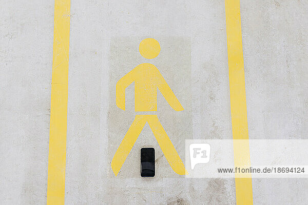 Smart phone below walking sign on floor in factory