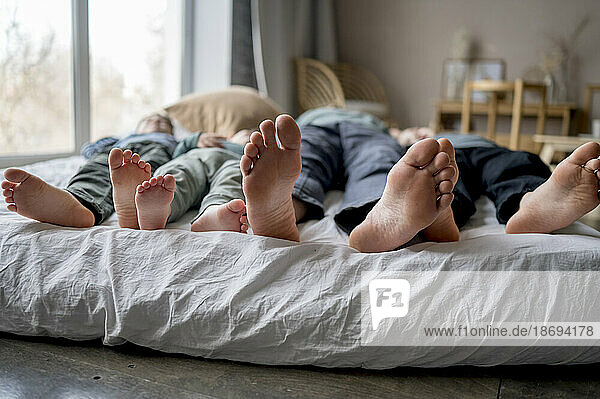 Father sleeping with sons on bed at home